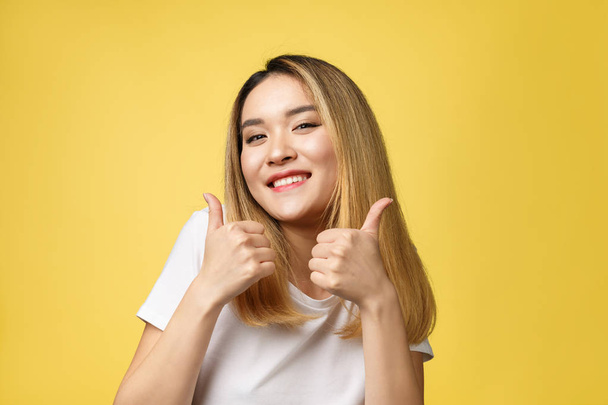 Jeune femme asiatique montrer pouces vers le haut sur fond jaune
 - Photo, image