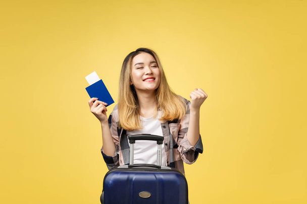 Viagem de mulher. Jovem bela mulher asiática viajante segurando passaporte, mala e bilhete de ar em pé sobre amarelo
. - Foto, Imagem