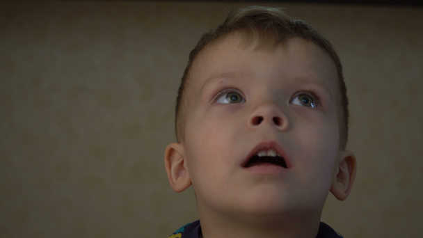 Detailní záběr na dva roky starý chlapec se dívá na televizi v temné místnosti. - Záběry, video