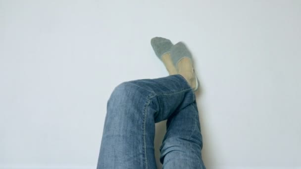 Woman legs up in jeans and socks relaxing up against a white wall - Кадры, видео