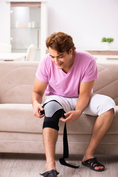 Młody człowiek z poszkodowanej kolana odzyskiwanie w domu - Zdjęcie, obraz