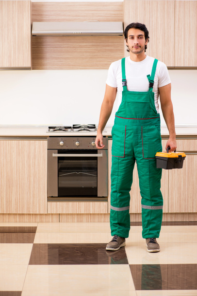 joven contratista reparación de horno en la cocina  - Foto, Imagen