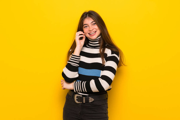 Young woman over yellow wall smiling with a sweet expression - Foto, afbeelding