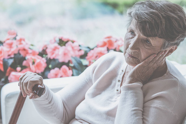 Sad old lady with cane sitting alone at home - Valokuva, kuva
