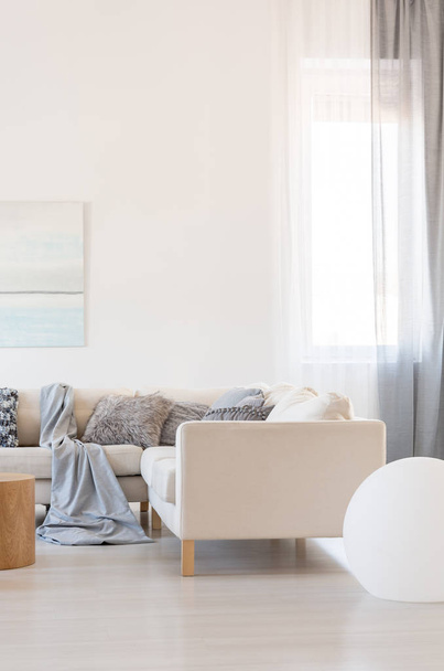 Вертикальний вид на яскравий інтер'єр вітальні з кутовим диваном з подушками
 - Фото, зображення
