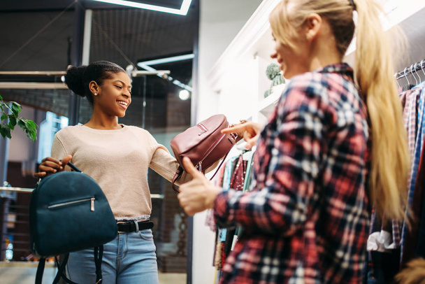 Δύο γυναίκες επιλέγουν τσάντες στο κατάστημα, ψώνια. Shopaholics σε κατάστημα ειδών ένδυσης, lifestyle καταναλωτισμού, μόδας - Φωτογραφία, εικόνα