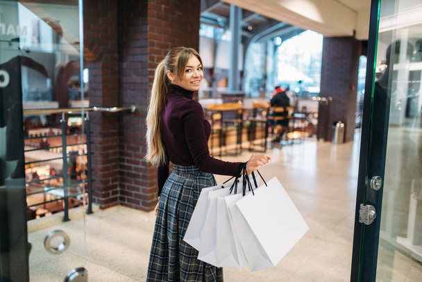 Νεαρή γυναίκα με τσάντες για ψώνια σε εμπορικό κέντρο. Shopaholic σε κατάστημα ειδών ένδυσης, lifestyle καταναλωτισμού, μόδας, ελκυστικό κυρία αγορά στο κατάστημα - Φωτογραφία, εικόνα