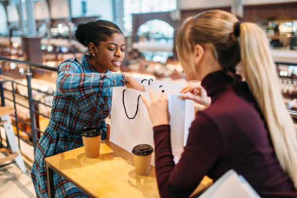 Zwei Damen trinken nach dem Einkauf Kaffee im Imbiss. Shopaholics in Bekleidungsgeschäften, Konsumlebensstil, Mode, Shopperinnen mit Taschen - Foto, Bild
