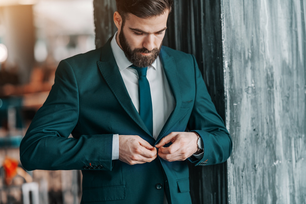 Κοντινό πλάνο του όμορφος Καυκάσιος επιχειρηματία κουμπιά από μπουφάν ενώ στέκεται εξωτερική. - Φωτογραφία, εικόνα