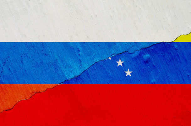 Σημαία της Βενεζουέλας και της Ρωσίας σχετικά με το ιστορικό της υφής του ξεφτισμένο χρώμα με μια ρωγμή σε ολόκληρο το πλαίσιο. Οριζόντιο πλαίσιο - Φωτογραφία, εικόνα