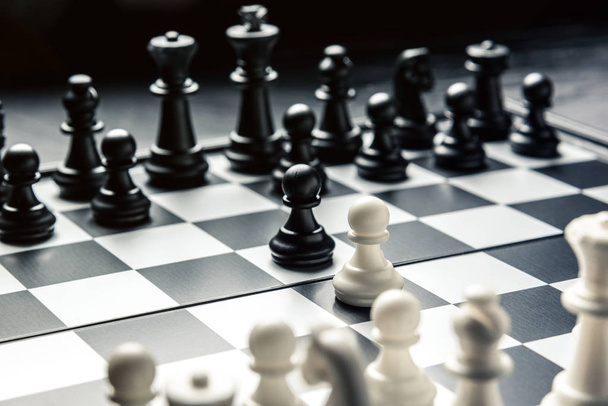 Σκακιέρα με μαύρο και άσπρο σκάκι αντικριστά. Λευκά και μαύρα πιόνια πάμε για την επίθεση. Οριζόντιο πλαίσιο - Φωτογραφία, εικόνα