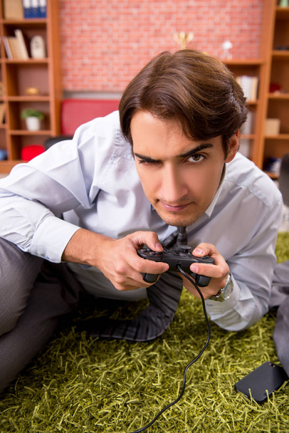 Νεαρός υπάλληλος παίζει παιχνίδια joystick κατά τη διάρκεια του διαλείμματος  - Φωτογραφία, εικόνα