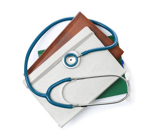 Stethoscope and notebooks on white background, top view. Medical students stuff - Photo, image