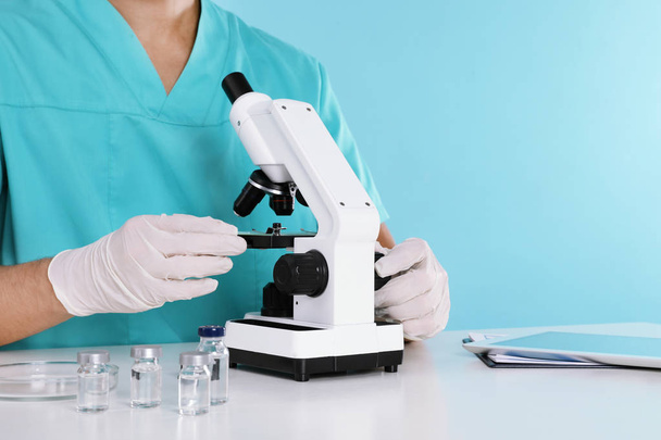 Male doctor using microscope at table, closeup with space for text. Medical object - Zdjęcie, obraz