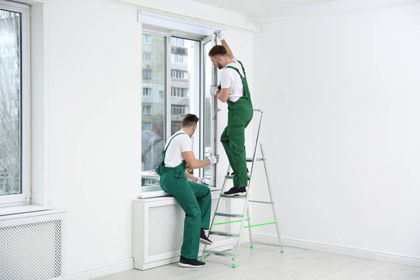 Construction worker using suction lifter during window installation indoors - Φωτογραφία, εικόνα