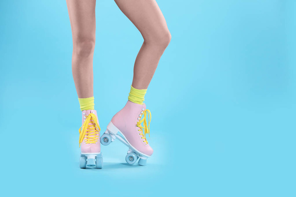 Young woman with retro roller skates on color background, closeup. Space for text - Valokuva, kuva