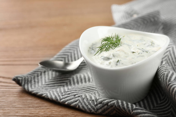 Cucumber sauce with spoon on wooden background, space for text. Traditional Tzatziki - Photo, Image