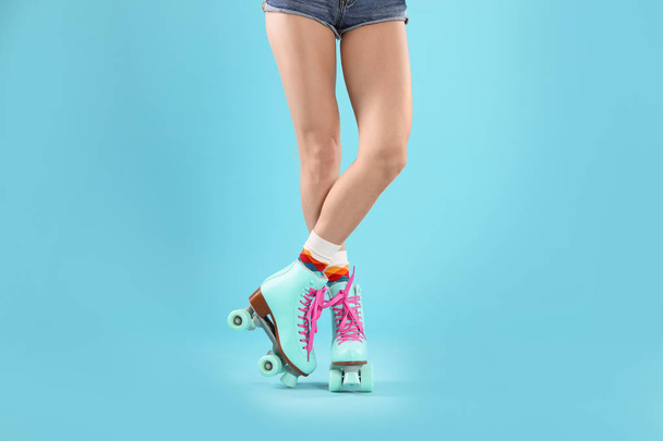 Young woman with retro roller skates on color background, closeup - Φωτογραφία, εικόνα