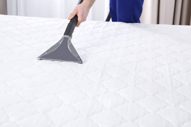 Man disinfecting mattress with vacuum cleaner, closeup. Space for text - Zdjęcie, obraz