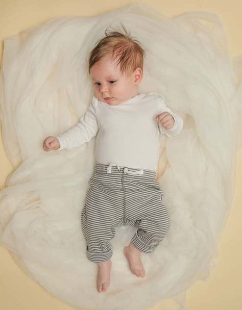 Suloinen kahden kuukauden ikäinen vauva kääritty valkoiseen kankaaseen
 - Valokuva, kuva