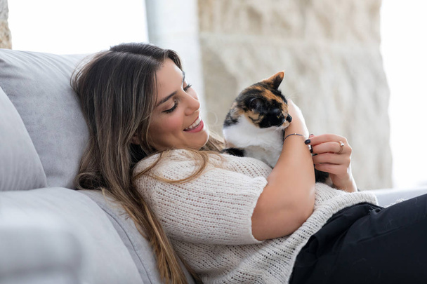 Close up van vrouwelijke eigenaar haar mooie zwart-witte kat thuis te houden. Concept van de liefde voor dieren, huisdieren, verzorging, rust. - Foto, afbeelding