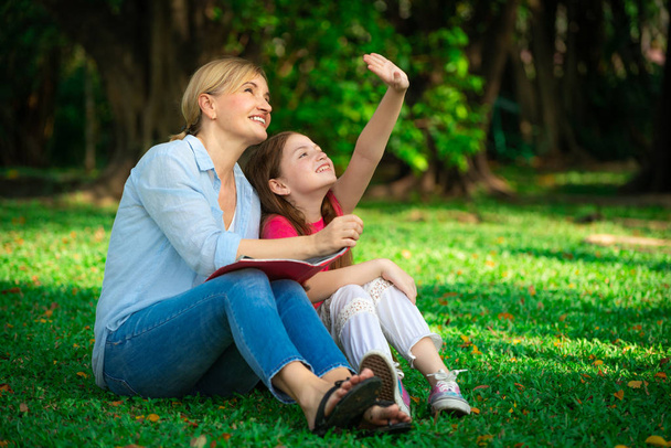 Расслабленная счастливая мать и маленькая дочка в общественном парке. Концепция отцовства и детства
. - Фото, изображение
