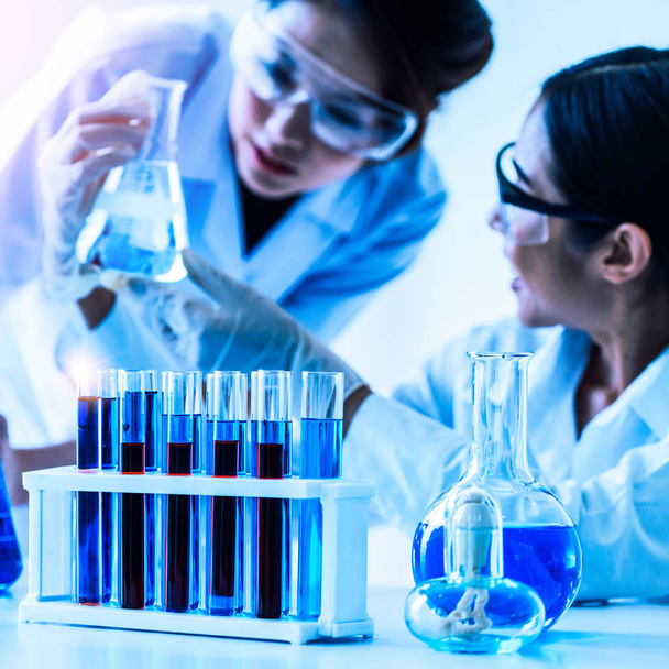 Ryhmä tiedemiehiä yllään lab takki työskentelevät laboratoriossa tutkiessaan biokemian näyte koeputkessa ja tieteellisiä välineitä. Tiedeteknologian tutkimus- ja kehittämistutkimuksen konsepti. - Valokuva, kuva