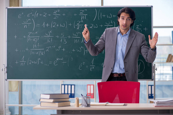 Молодой красивый учитель математики в классе
  - Фото, изображение