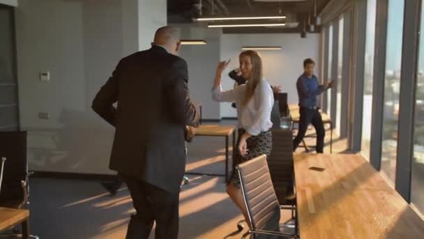 Liikemiehet tanssivat iloisesti toimistossa kameran edessä
 - Materiaali, video