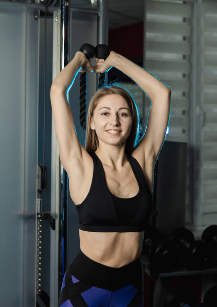 Actieve mooie fitness model meisje traint triceps op het blok in de sportschool. - Foto, afbeelding
