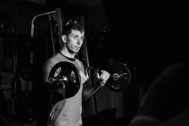 Atletický muž vlaky činka biceps v tělocvičně. - Fotografie, Obrázek