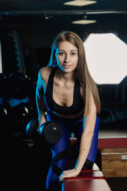 Seitenansicht der schönen Fitness-Frau beim Training mit Gewichten über der Trainingsbank im Fitnessstudio. - Foto, Bild