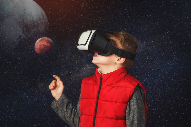 Een jongen met een virtuele headset spelen van een spel over de ruimte. Virtual reality en moderne technologieën - Foto, afbeelding