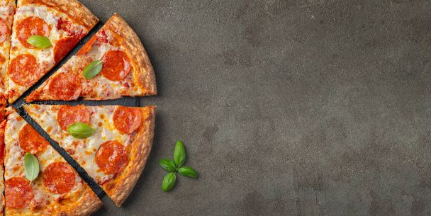 Tasty pepperoni pizza with basil on brown concrete background. Top view of hot pepperoni pizza. With copy space for text. Flat lay. - Photo, image