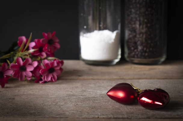 corazones de plástico rojo colocados en una mesa de madera Hay una flor colocada en la parte posterior izquierda y hay
 - Foto, imagen