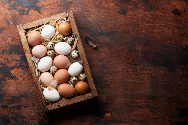 Uova di gallina e quaglia in scatola su tavolo di legno. Biglietto di auguri pasquale. Vista dall'alto con spazio per i vostri saluti
 - Foto, immagini