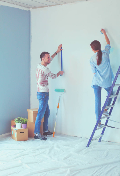 Portrait of happy smiling young couple painting interior wall of new house. young couple - Fotoğraf, Görsel