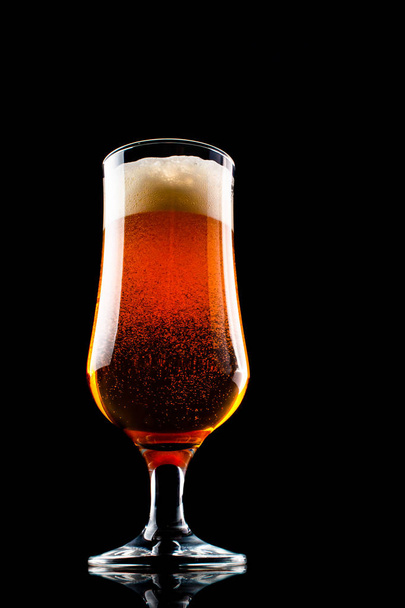 Um copo de cerveja com espuma isolada em fundo preto
 - Foto, Imagem