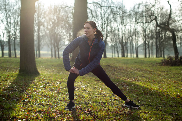 Kobieta rozgrzewki ćwiczenia rano z rozciąga się w Winter Park - Zdjęcie, obraz
