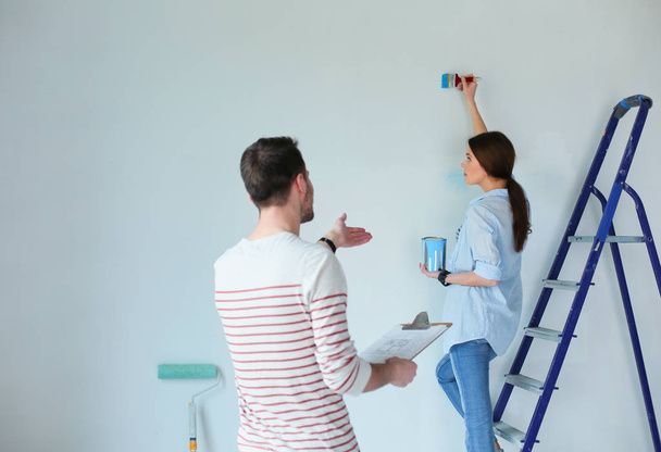 Portrait of happy smiling young couple painting interior wall of new house. young couple - Photo, image