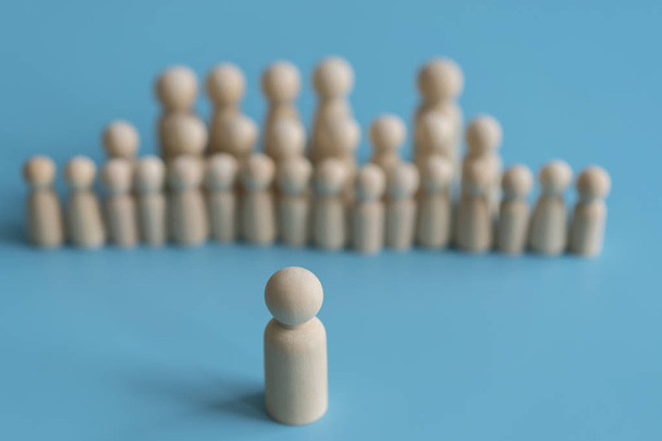 The concept of society. Stand out from the crowd, not like everyone else, leadership. Standing Out From The Crowd. Wooden figures on a blue background - Photo, Image