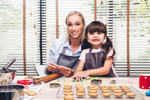 Мама и дочь весело готовят вместе и учатся печь торт, пока пекут дома на кухне - Фото, изображение