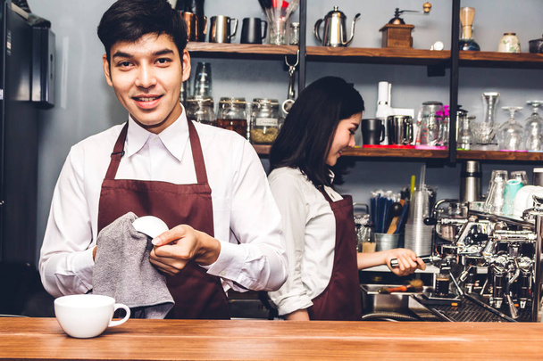 Πορτραίτο του ιδιοκτήτης μικρής επιχείρησης ζευγάρι χαμογελώντας και λειτουργεί πίσω από τη γραμμή μετρητή σε μια καφετέρια. Ζευγάρι barista χρησιμοποιώντας καφετιέρα για καφέ στο καφενείο - Φωτογραφία, εικόνα