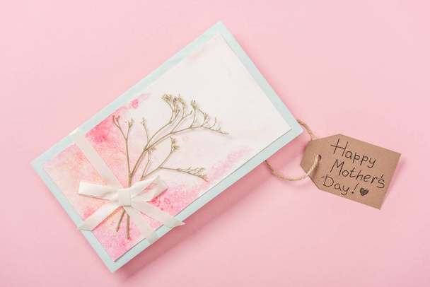 üdvözlőlap díszített szárított növényi, az íj és a fából készült címke Boldog anyák napi köszöntő szöveg rózsaszín háttér - Fotó, kép