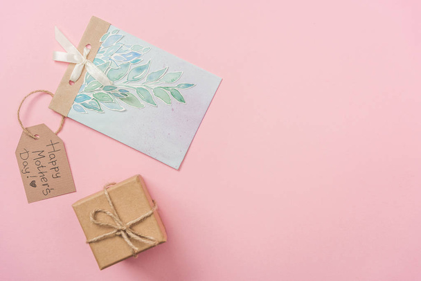 gift box, mothers day greeting card and wooden label with happy mothers day greeting text on pink background  - 写真・画像