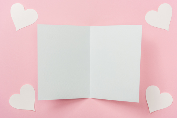 Tarjeta de felicitación en blanco y corazones de papel blanco sobre fondo rosa - Foto, imagen
