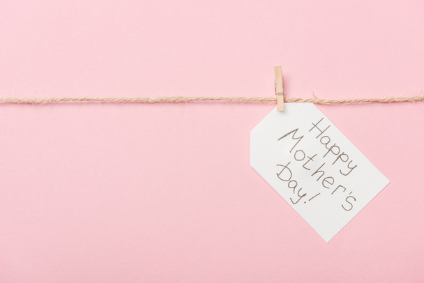 white paper label with happy mothers day greeting with coarse thread on pink background - Foto, immagini