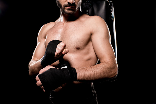 bijgesneden beeld van shortless sportman verpakken omhoog handschoenen geïsoleerd op zwart - Foto, afbeelding