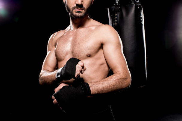 cropped view of shortless athlete wrapping up gloves on black background - Fotografie, Obrázek