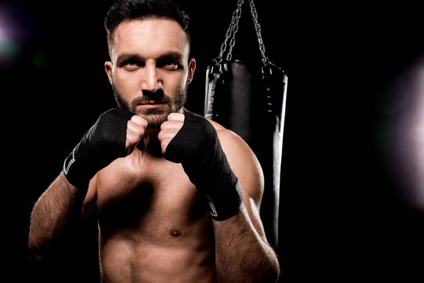 handsome sportsman standing in boxing pose on black background - Foto, Imagen